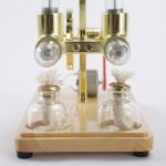 Dispositivo di laboratorio con due bottiglie di vetro collegate a un apparato di ottone, utilizzato per esperimenti scientifici e dimostrazioni di chimica.