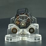 Modello di motore a razzo in miniatura con dettagli tecnici visibili, esposto su base trasparente, ideale come decorazione scientifica o oggetto da collezione.