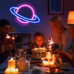 Famiglia che celebra un compleanno con decorazioni scientifiche luminose e neon, tra cui un pianeta con anelli, creando un'atmosfera divertente e educativa.