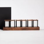 Set di sei oggetti scientifici in vetro con coperchi in legno, posizionati su una base in legno, ideale come decorazione o oggetto da collezione.