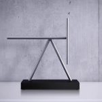 Oggetto scientifico moderno in metallo con base nera, design minimalista e linee pulite, ideale come decorazione da scrivania o oggetto da collezione ispirato alla scienza.