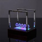 Péndolo di Newton con sfere luminose LED, oggetto decorativo scientifico, perfetto per appassionati di fisica e design innovativo.