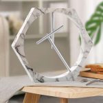 Orologio da parete decorativo in marmo con cornice a forma di esagono e lancette minimaliste, perfetto per arredare con stile moderno e scientifico.