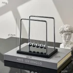 Pendolo di Newton in metallo e vetro, perfetto come decorazione scientifica per studi e uffici, con sferette oscillanti e design elegante.