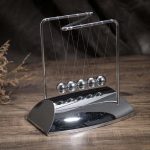 Péndolo di Newton in metallo lucido, oggetto decorativo scientifico, perfetto per appassionati di fisica e design innovativo.