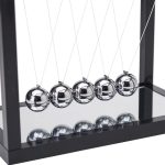 Péndoli di Newton in vetro riflettente, oggetto scientifico decorativo con cinque sfere sospese in un supporto nero, ideale per decorazioni e studi di fisica.