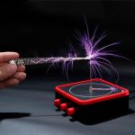 Immagine di una scintilla di plasma generata da un dispositivo di controllo elettronico, con fili di energia visibili e un'area di lavoro nera.
