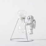Decorazione scientifica con astronauta e clessidra in stile minimalista, perfetta per appassionati di scienza e decorazioni originali.