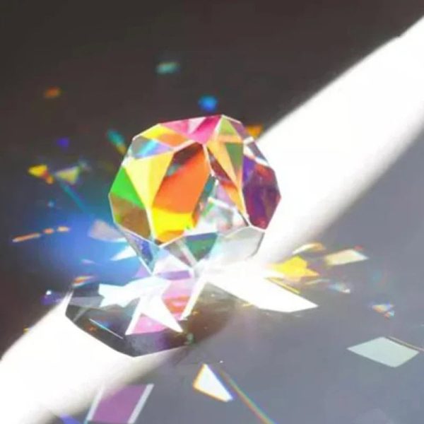 Cristallo di cristallo colorato con riflessi arcobaleno, posato su una superficie bianca con giochi di luce e riflessi. Perfetto come decorazione scientifica o oggetto da collezione.