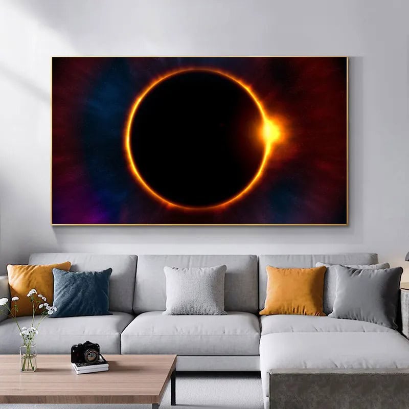 Immagine di un'eclissi solare artistica rappresentata come un cerchio luminoso con un alone arancione e sfumature di blu e rosso, appesa sopra un divano moderno in un soggiorno minimalista.