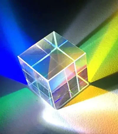 Cubo di vetro trasparente che riflette luci di vari colori, creando effetti di luce e ombra su superfici vicine. Perfetto come decorazione scientifica o oggetto da collezione.