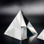 Piramide di cristallo decorativa con riflessi iridescenti, perfetta come oggetto scientifico e decorativo per ambienti moderni e studi di design.