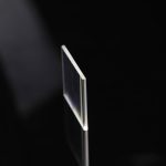 Pannello di vetro trasparente utilizzato in esperimenti scientifici, con sfondo nero per evidenziare la sua trasparenza e precisione.