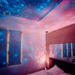Decorazione luminosa con proiezione di stelle e galassie sulla parete e soffitto di una stanza, creando un'atmosfera magica e spaziale. Perfetta per ambienti di relax o decorazioni a tema astronomico.
