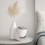 Oggetto scientifico decorativo in vaso bianco, posizionato su un tavolo di pietra, con sfondo neutro e ambiente elegante.