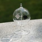 Vaso di cristallo trasparente con globulo di vetro e supporto, oggetto decorativo scientifico.