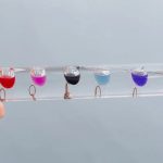 Esperimento con coloranti in provette di vetro sospese in acqua, mostrare la miscelazione di colori in un setup scientifico decorativo.