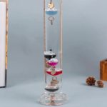 Pendolo di vetro con anelli metallici e decorazioni in resina colorata, ideale come oggetto decorativo scientifico o da collezione.