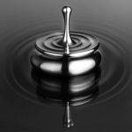Immagine di una pietra dell'acqua in rilievo che crea un effetto di goccia d'acqua che si riflette su una superficie liscia e scura.