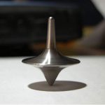 Tornado di metallo in equilibrio su una superficie, con ombra visibile, simbolo di equilibrio e precisione scientifica.