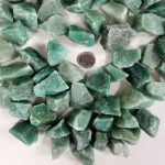 Pietre di giada verde di varie forme e dimensioni, ideali per decorazioni scientifiche, collezioni e progetti educativi, con una moneta per dimensione di riferimento.