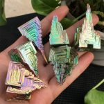 Cristalli metallici iridescenti con forma geometrica, perfetti come decorazioni scientifiche o oggetti da collezione, con riflessi colorati e superfici lucide.