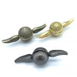 Decorazioni scientifiche con oggetti a forma di capsule con ali, in finiture oro e argento, ideali per arredamento e collezionismo.