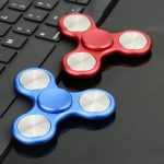 Fidget spinner blu e rosso su tastiera, oggetti decorativi e antistress con design scientifico.