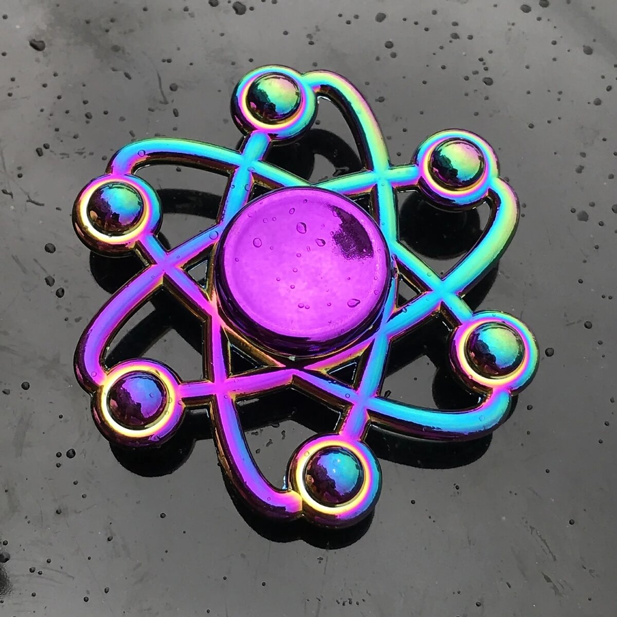 Modello atomico colorato Simbolo atomico in metallo con finitura iridescente, rappresenta un atomo stilizzato con orbite e nucleo centrale.