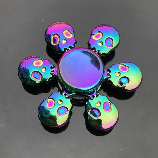 Pendente decorativo con sette teschi in metallo iridescente, disposti a formare un fiore, ideale come decorazione o accessorio originale.