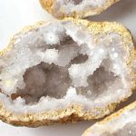 Geode cristallina naturale con cristalli bianchi e superficie ruvida, perfetta come oggetto decorativo o da collezione.