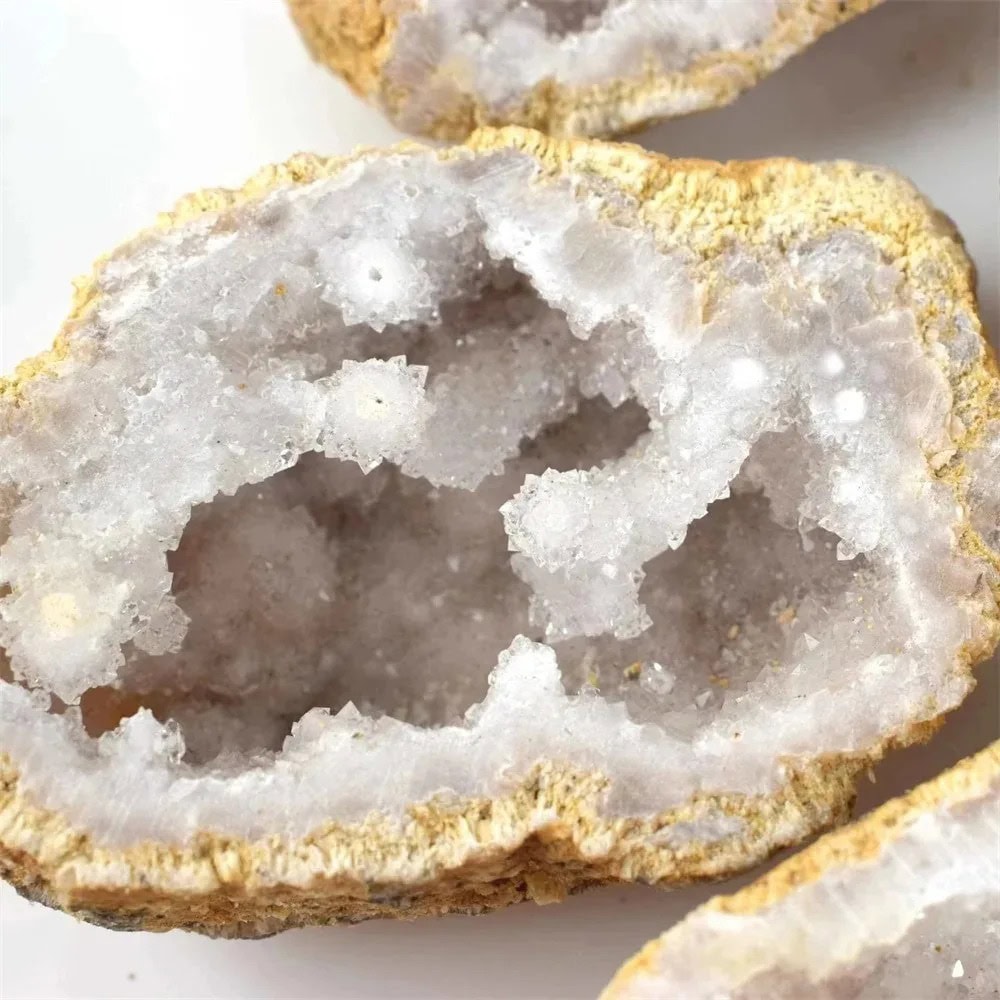 Pietra geode cristallina naturale Geode cristallina naturale con cristalli bianchi e superficie ruvida, perfetta come oggetto decorativo o da collezione.