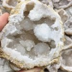 Geode cristallina bianca con cristalli scintillanti e superficie ruvida.