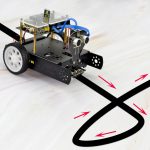 Robot educativo con sensori e linee di tracciamento su superficie bianca, utilizzato per insegnare robotica e programmazione ai studenti.