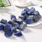 Pietre di lapislazzuli blu, perfette per decorazioni e progetti scientifici, disposte su un piatto bianco con sfondo luminoso.