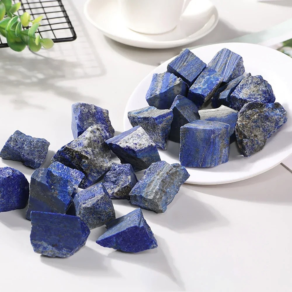 Pietre di lapislazzuli blu, perfette per decorazioni e progetti scientifici, disposte su un piatto bianco con sfondo luminoso.