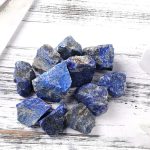 Pietre di lapislazzuli blu naturale, perfette come decorazioni scientifiche o oggetti da collezione, su sfondo di legno bianco.