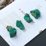 Malachite, minerale verde intenso, posizionata su una rivista con testo in italiano. Perfette come decorazioni scientifiche o oggetti da collezione.