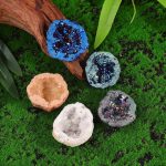 Vasi di cristallo decorativi con glitter in vari colori, ideali come oggetti decorativi scientifici e per la casa, posizionati su un prato verde con elementi naturali.