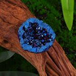 Pietra decorativa con cristalli blu e nero su tronco di legno, perfetta come oggetto decorativo scientifico e artistico.