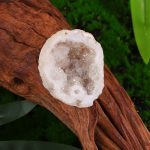 Geode di quarzo bianco su tronco di legno.