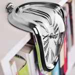 Orologio da parete con effetto distorto e design artistico, in stile surrealista, con quadrante che sembra sciogliersi e deformarsi, perfetto come decorazione originale per ambienti creativi.
