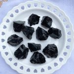 Pietre vulcaniche nere su piatto decorativo, perfette come oggetti scientifici o decorazioni per ambienti moderni e minimalisti.