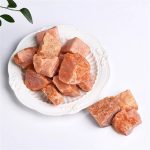 Cristalli di salgemma rosa naturale su piatto bianco, perfetti come decorazione o per uso culinario, con un aspetto cristallino e colore caldo.