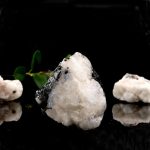 Pietra di ghiaccio naturale con foglie verdi, oggetto decorativo scientifico, su sfondo nero.