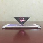 Oggetto scientifico con forma di cuore luminoso proiettato da un prisma su uno smartphone, decorazione originale e moderna per appassionati di scienza e tecnologia.