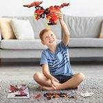 Bambino che gioca con un modello di drago LEGO rosso e nero, costruito con mattoncini LEGO, seduto sul tappeto in soggiorno.