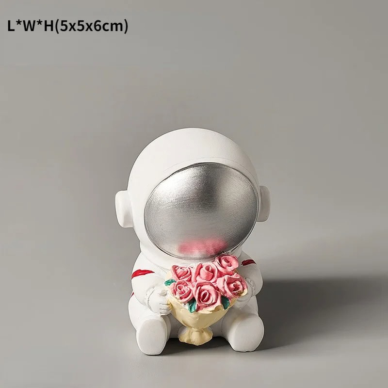 Oggetto decorativo astronauta con bouquet di rose Decorazione da scrivania a forma di astronauta con casco argentato e bouquet di rose rosa, perfetta come regalo o decorazione scientifica.