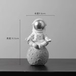 Figurina di astronauta in miniatura seduto su una luna, decorazione scientifica per appassionati di spazio e astronomia. Perfetta come oggetto decorativo o regalo tematico.