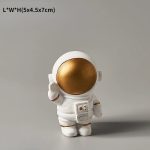 Statua di un astronauta in stile decorativo con casco dorato lucido, perfetta come oggetto da collezione o decorazione scientifica moderna.